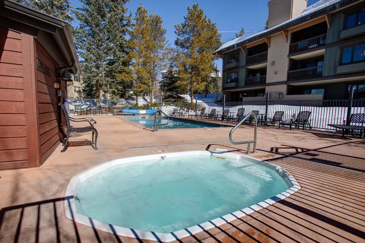A beautiful outdoor area with a heated swimming pool, bubbling hot tub, lounge chairs, and surrounding trees. The space is inviting for both relaxation and socializing, whether after winter sports or summer hikes.
