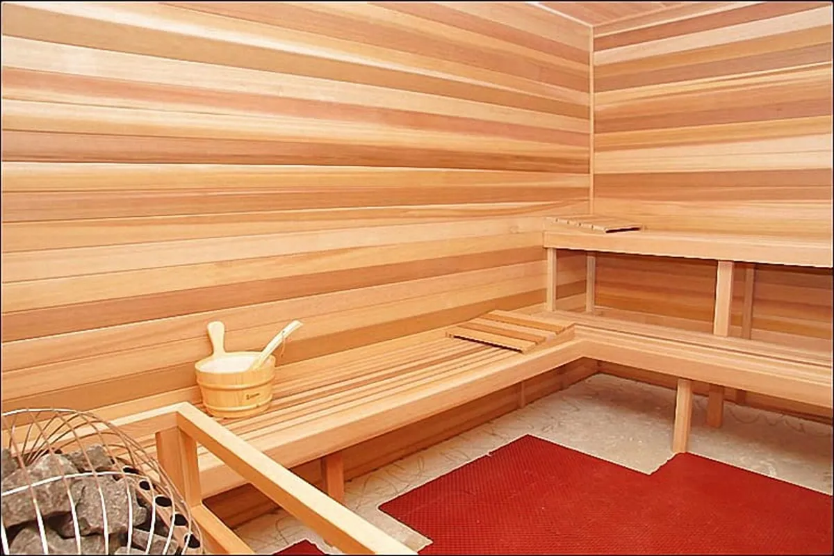 A cozy wooden sauna with benches, sauna stones, and a water bucket, inviting guests to unwind after a workout or day of adventure. The tranquil ambiance is perfect for relaxation and self-care.