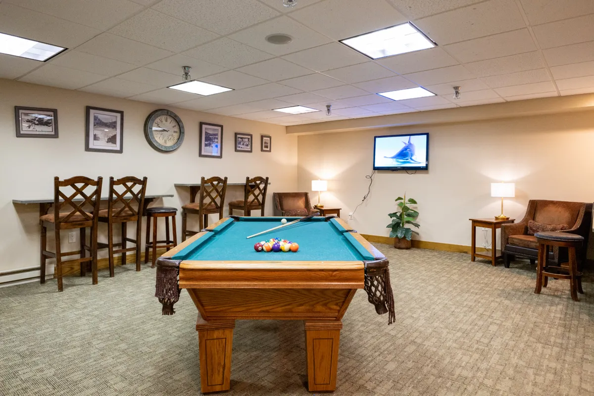 A stylish lounge space featuring a pool table, bar stools, a television, and comfortable seating. The playful yet relaxed atmosphere encourages social gatherings, friendly competitions, and group relaxation.