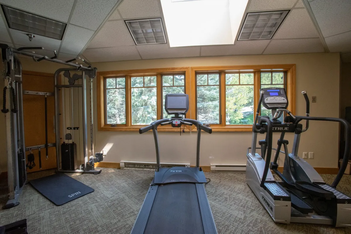 This bright, welcoming fitness center features modern equipment—treadmills, an elliptical, and a weight machine—alongside large windows that let in natural light and offer views outside. The space feels energizing and accessible for guests eager to keep up their fitness routines while on vacation.
