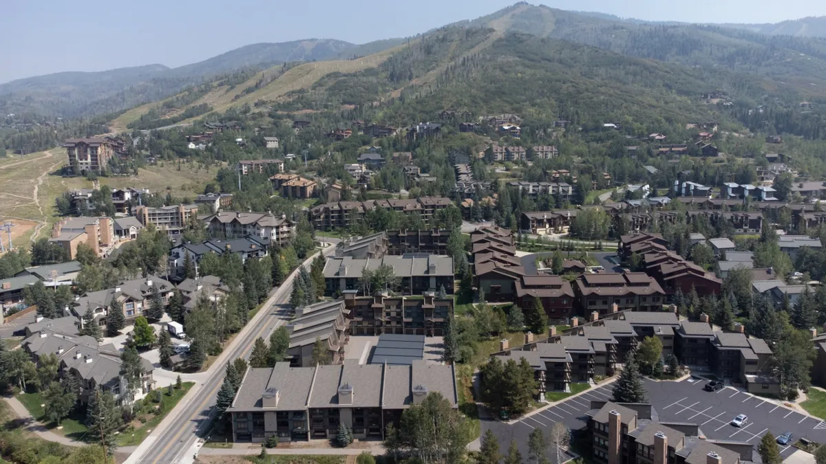 The hero image showcases a stunning panoramic view of the Steamboat Springs mountain range, with lush greenery and inviting residential condos nestled below. Winding roads lead into the vibrant community, suggesting easy access to outdoor adventures. The scene exudes a peaceful yet lively atmosphere, perfect for both relaxation and recreational activities.