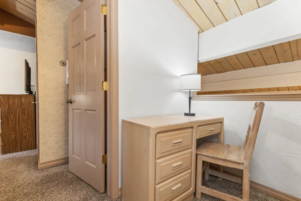 A dedicated workspace featuring a desk, lamp, and chair set against a warm, intimate backdrop. The space is designed for productivity, reading, or quiet reflection, making it ideal for guests who need to work remotely or seek a peaceful corner.